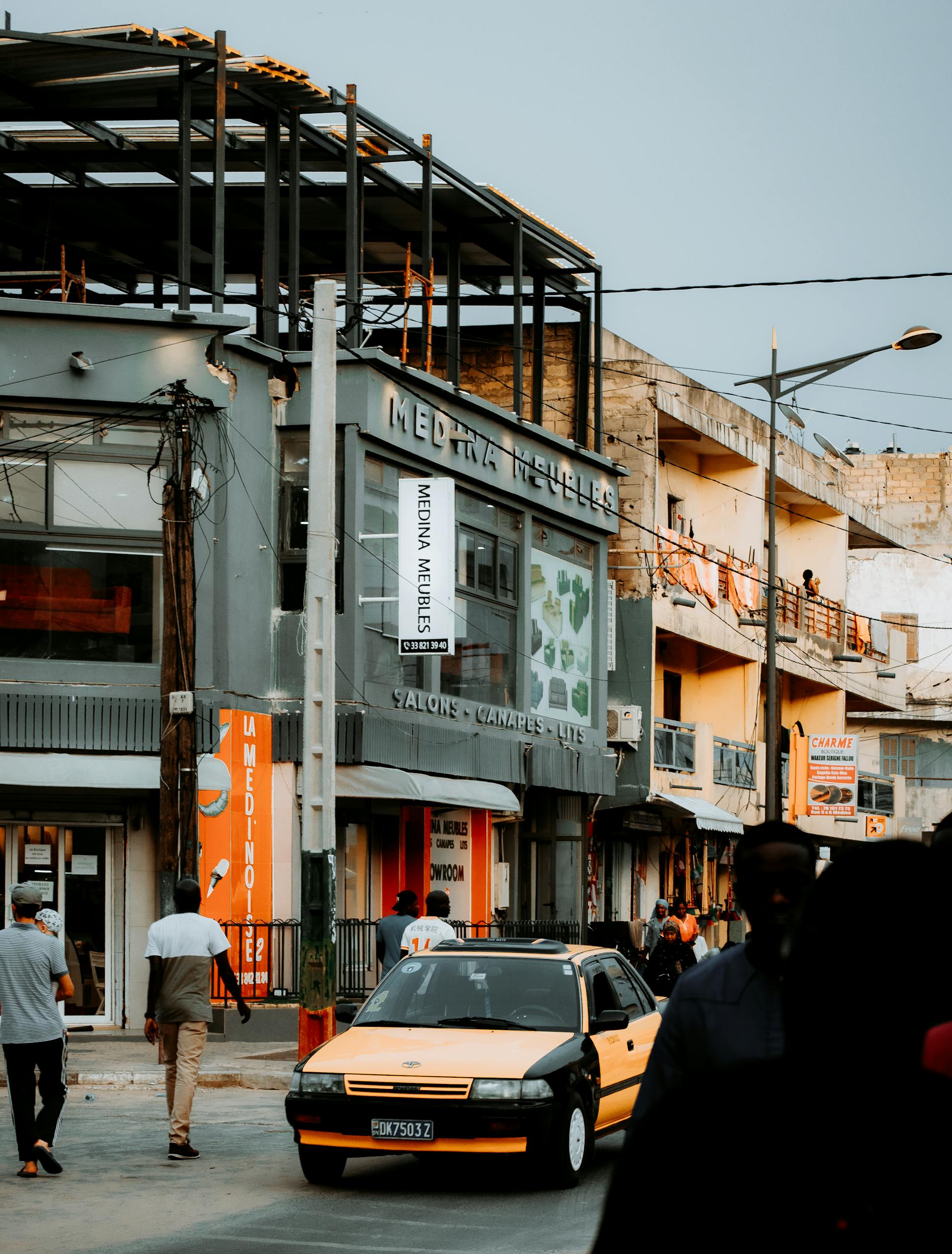 Street view of Dakar, Senegal featuring pedestrians, vehicles, and urban architecture.