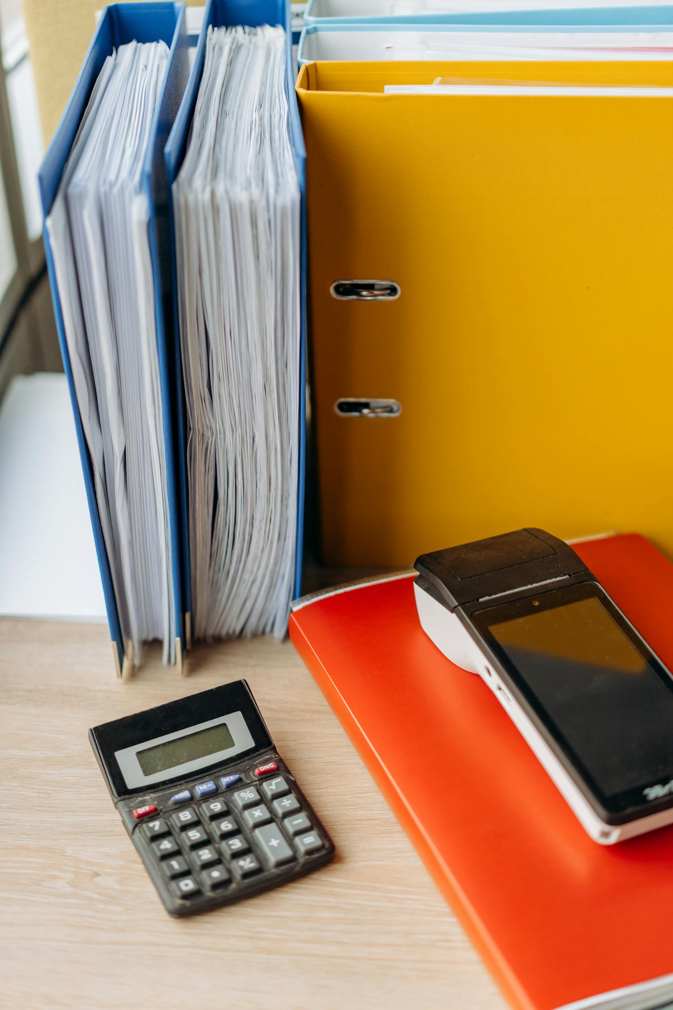 Organized office desk with a calculator, files, and documents for efficient work.
